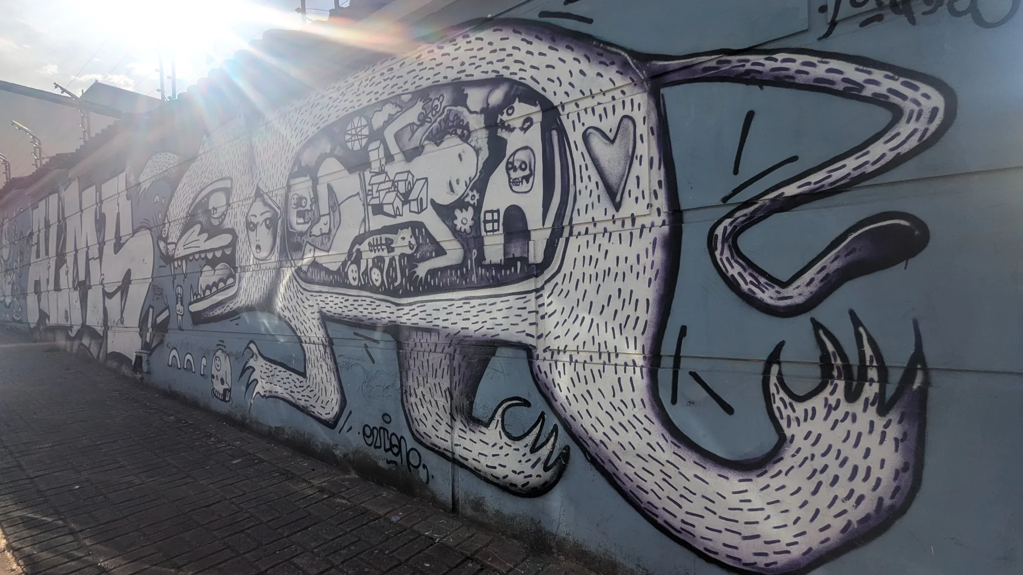 Un gran mural urbano muestra un rostro estilizado y líneas curvas sobre un muro.