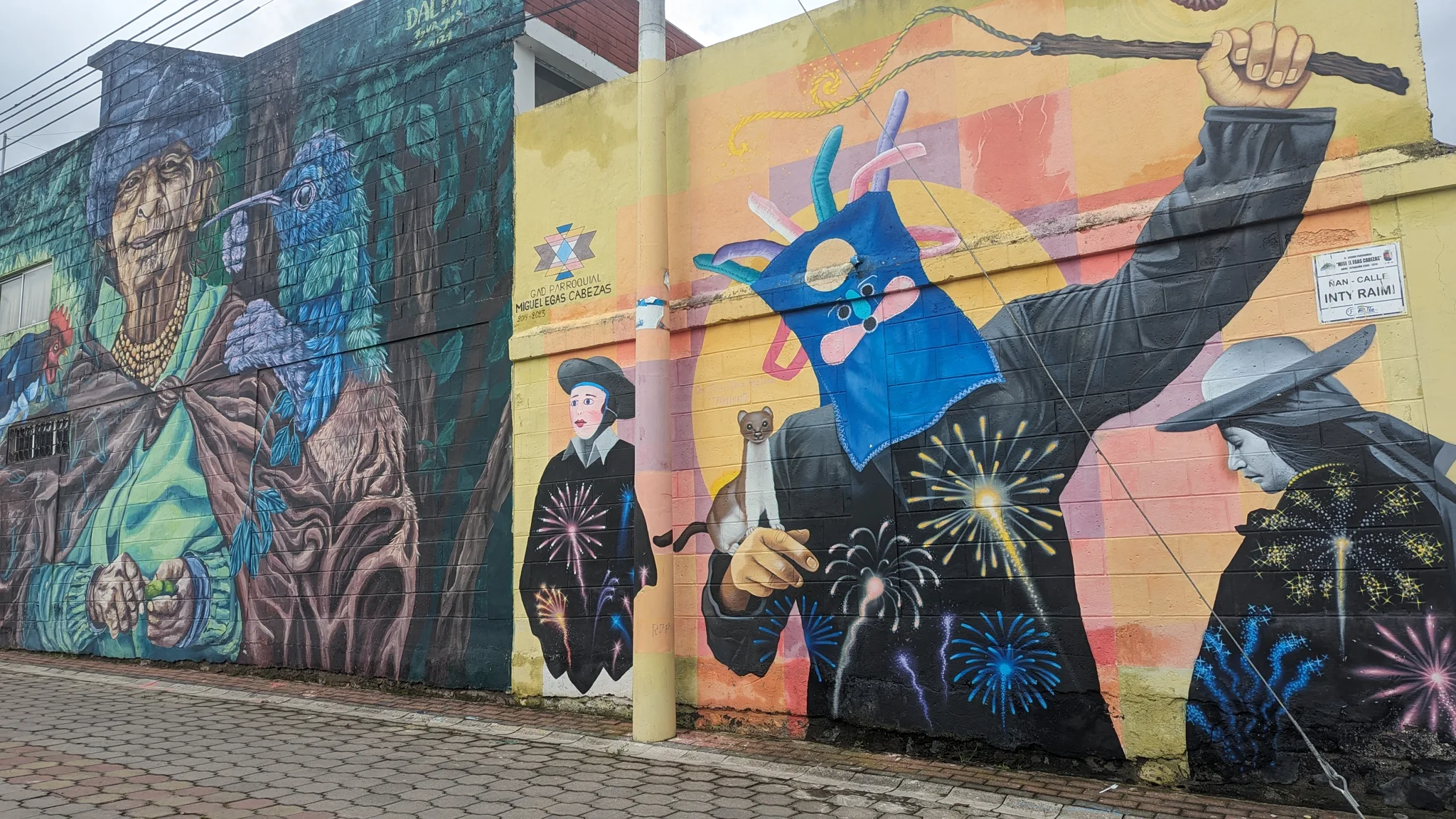 Un mural colorido con aves y figuras pintadas cubre un muro largo.