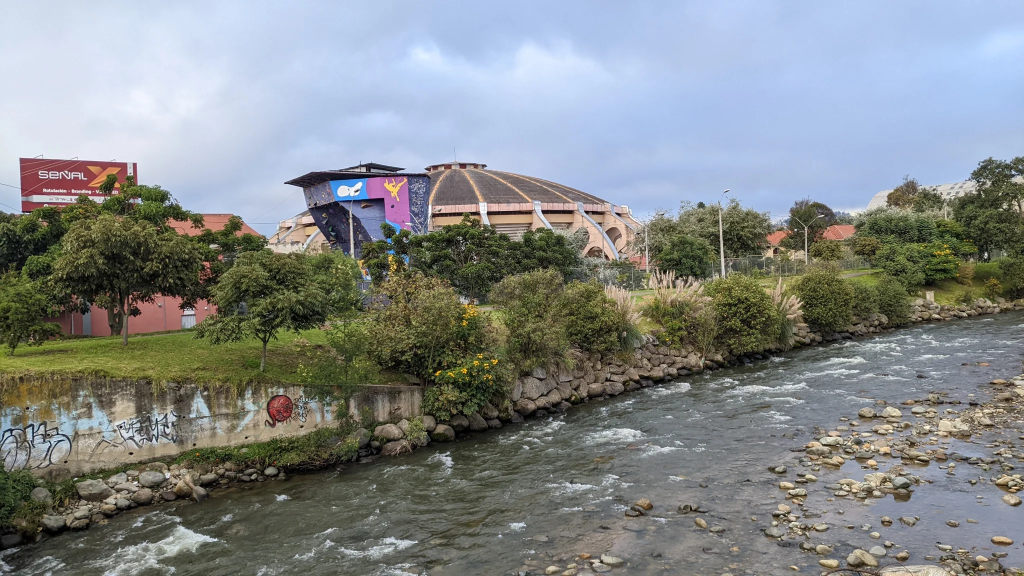 Un río pasa junto a edificios y un puente bajo un cielo nublado.
