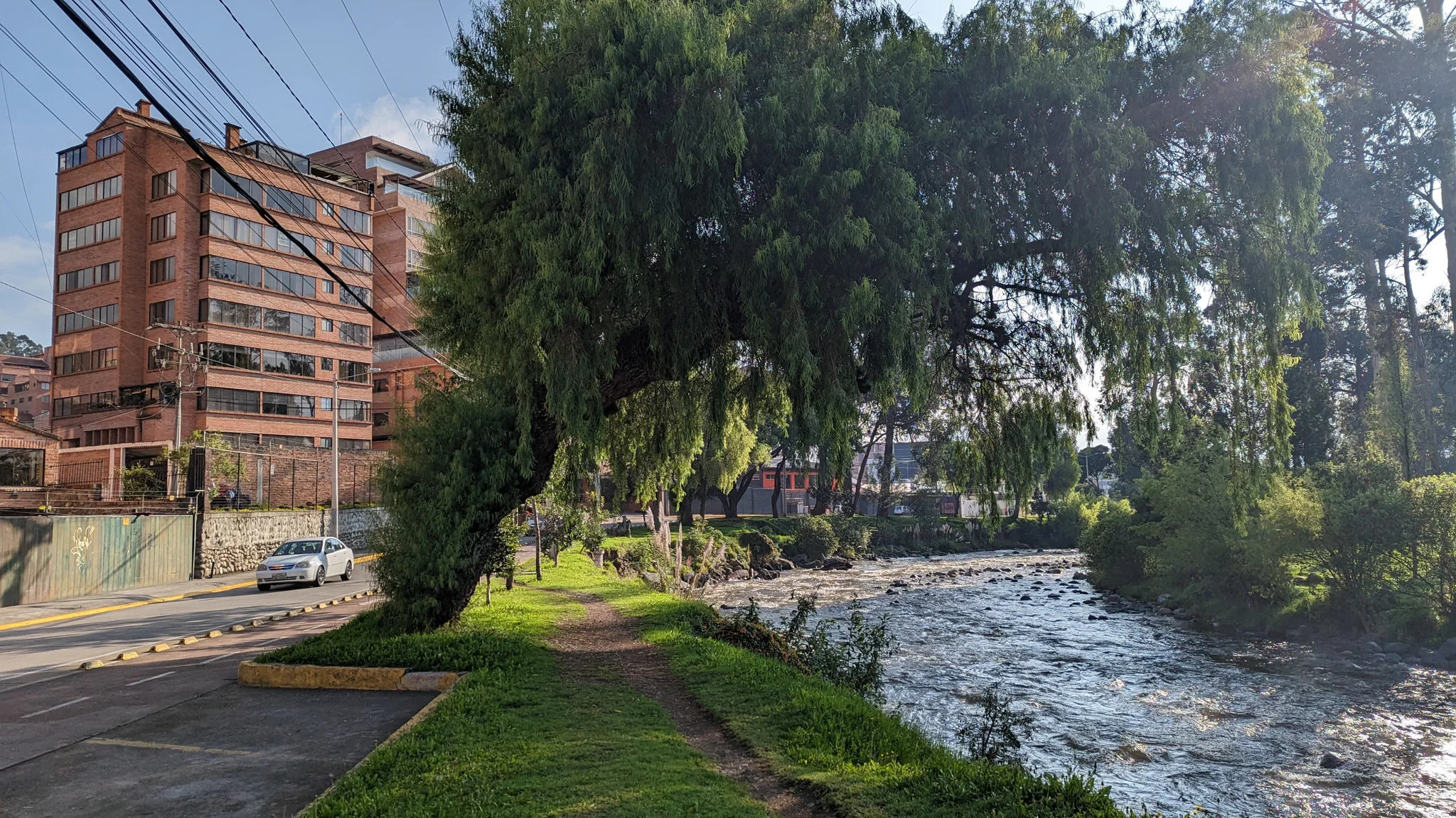 Un edificio de ladrillo rojo se levanta junto a una ribera con árboles.