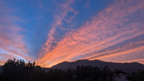 Rayos rosados sobre un horizonte oscuro de montaña