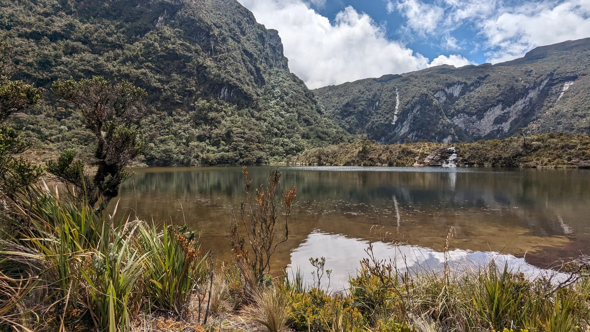 Una laguna pequeña al pie de laderas rocosas. El nombre del cuerpo de agua sigue sin confirmarse.