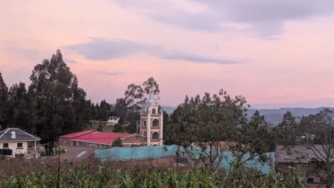 Una torre de iglesia bajo nubes rosadas