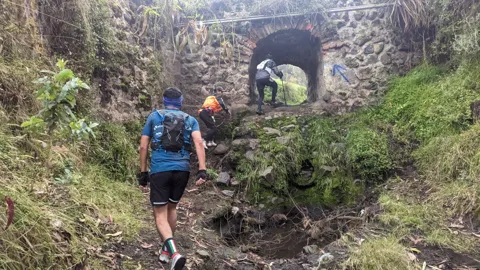 Un acceso lodoso a un arco de piedra