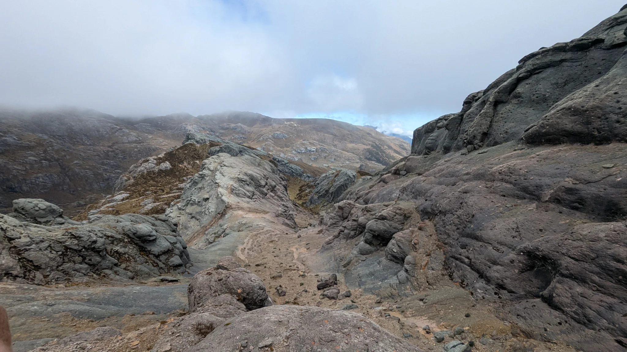 Losas de roca pulida forman un corredor sinuoso que se pierde en la niebla de altura.