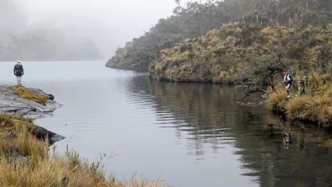 Caminantes en ambos lados de una entrada de agua. El nombre del cuerpo de agua sigue sin confirmarse.