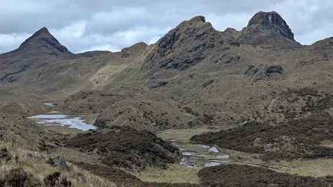 Un pequeño humedal bajo cumbres rocosas. El nombre del cuerpo de agua sigue sin confirmarse.