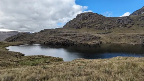 Una laguna redonda bajo una cumbre rocosa