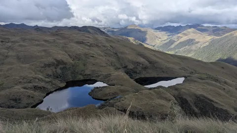 Dos lagunas oscuras bajo crestas altas. El nombre del cuerpo de agua sigue sin confirmarse.