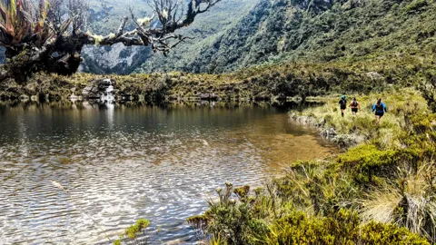 Caminantes en la orilla de una laguna. El nombre del cuerpo de agua sigue sin confirmarse.