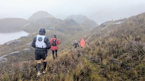 Caminantes con capucha sobre una laguna con niebla. El nombre del cuerpo de agua sigue sin confirmarse.