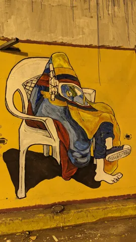 Una figura sentada en una pared amarilla